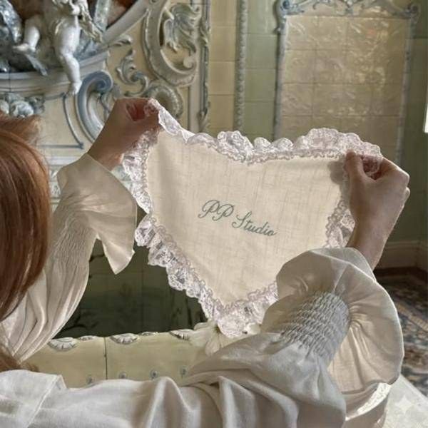A heart-shaped linen and lace invitation embroidered with PP Studio in script